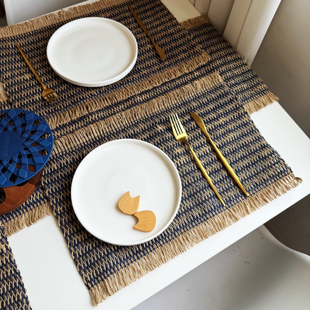Sailorine dark striped placemats with white plates and gold-colored cutlery