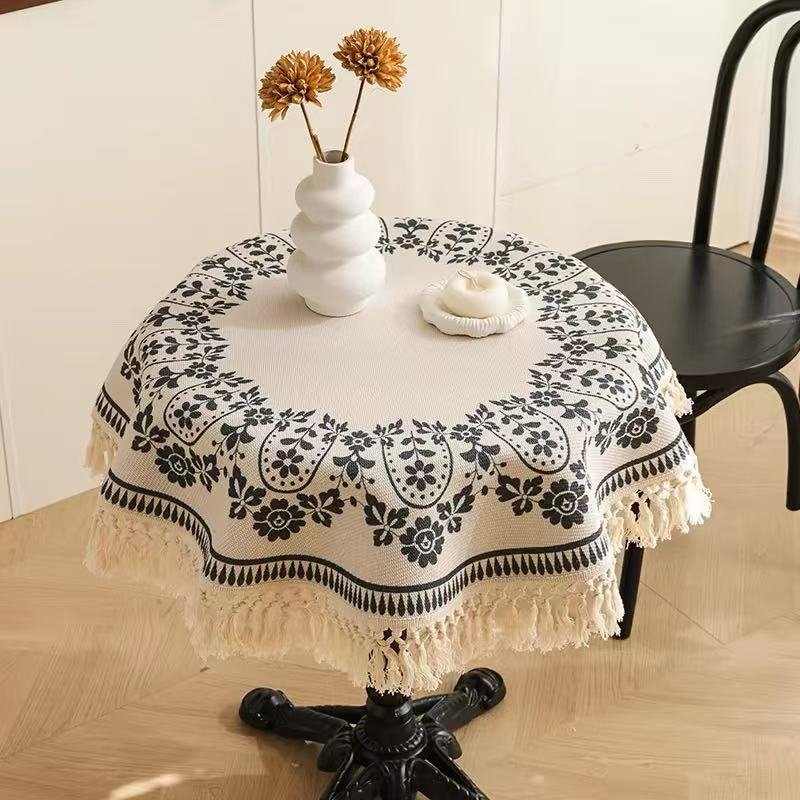 Sailorine cream round tablecloth with dark floral motifs beneath a vase