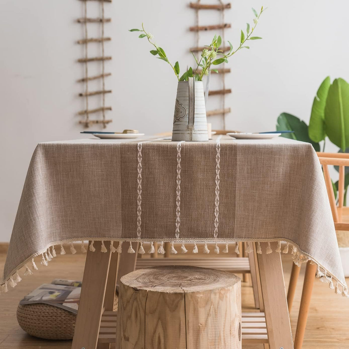 Sailorine striped neutral tablecloth on a table beneath a leafy vase