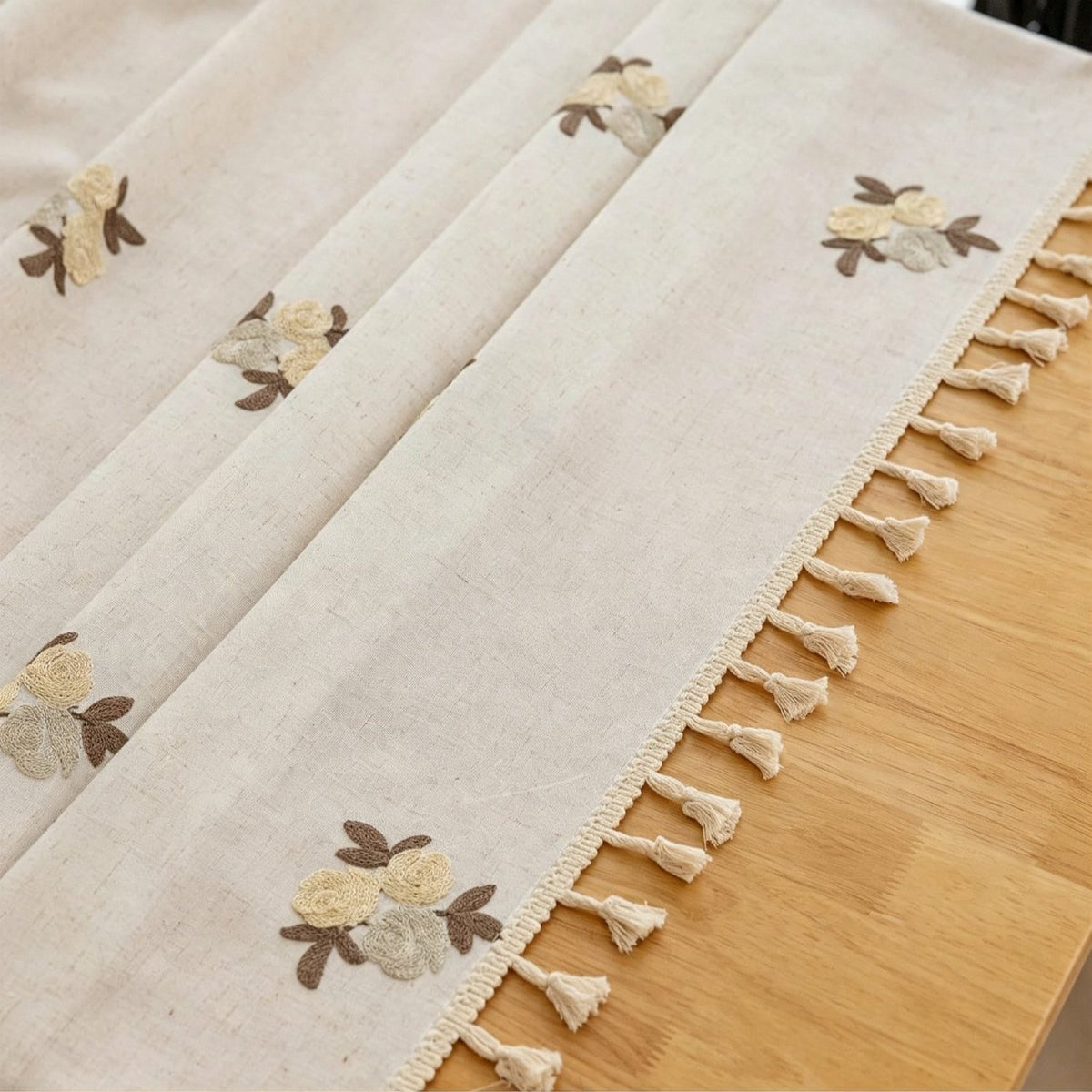 Sailorine close-up of floral embroidery-style motifs and tasseled tablecloth edge