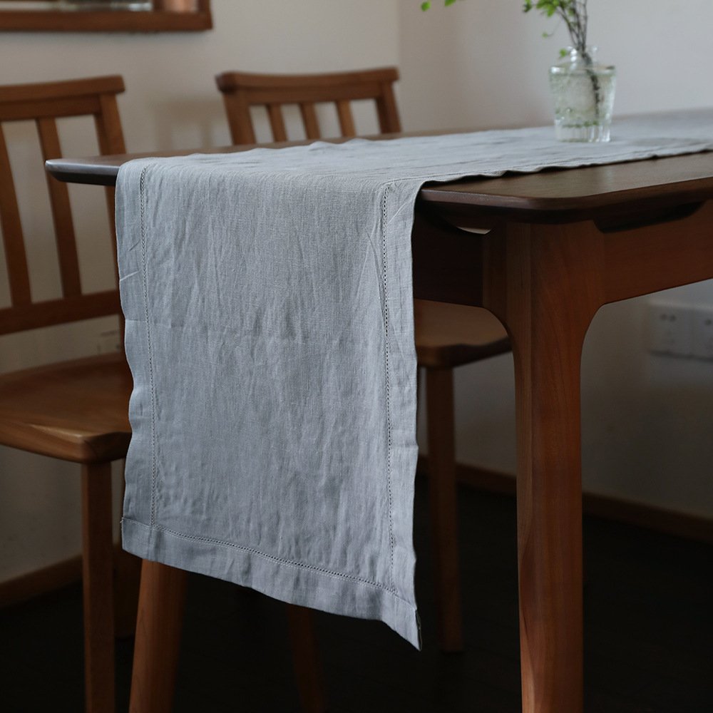Sailorine gray table runner draped over a dark wooden dining table