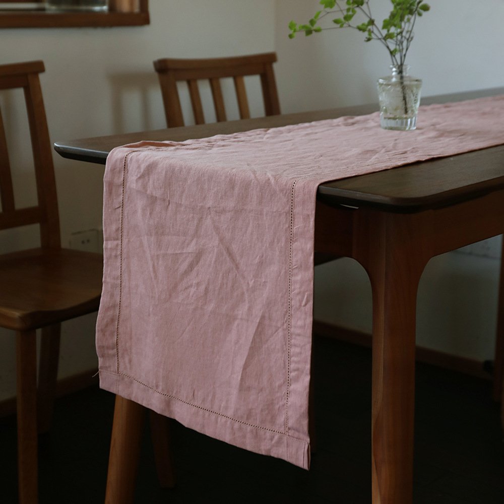 Sailorine dusty pink table runner on a wooden table with a glass vase